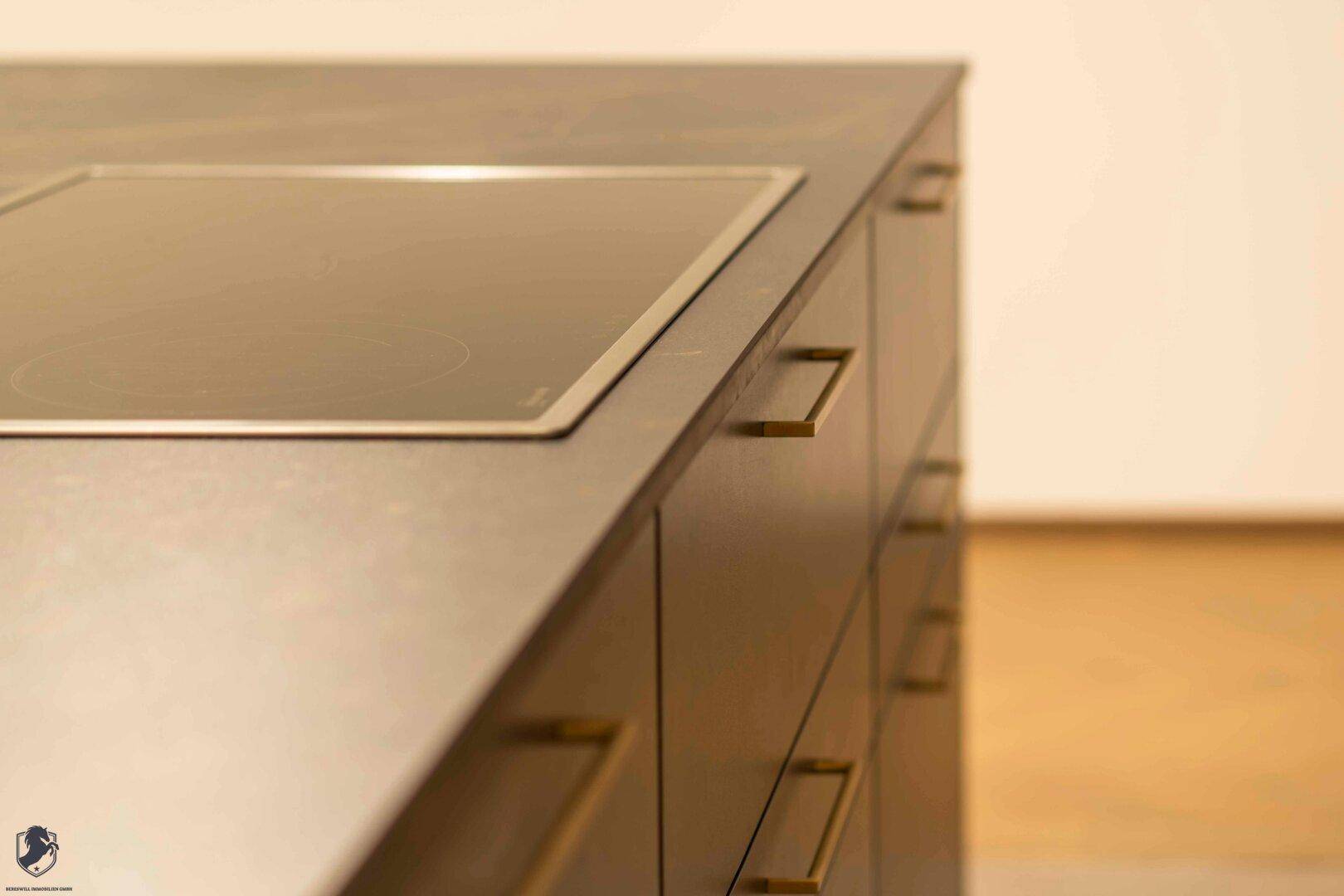 Nahaufnahme der modernen Kücheninsel mit integriertem Induktionskochfeld und eleganten Griffen.