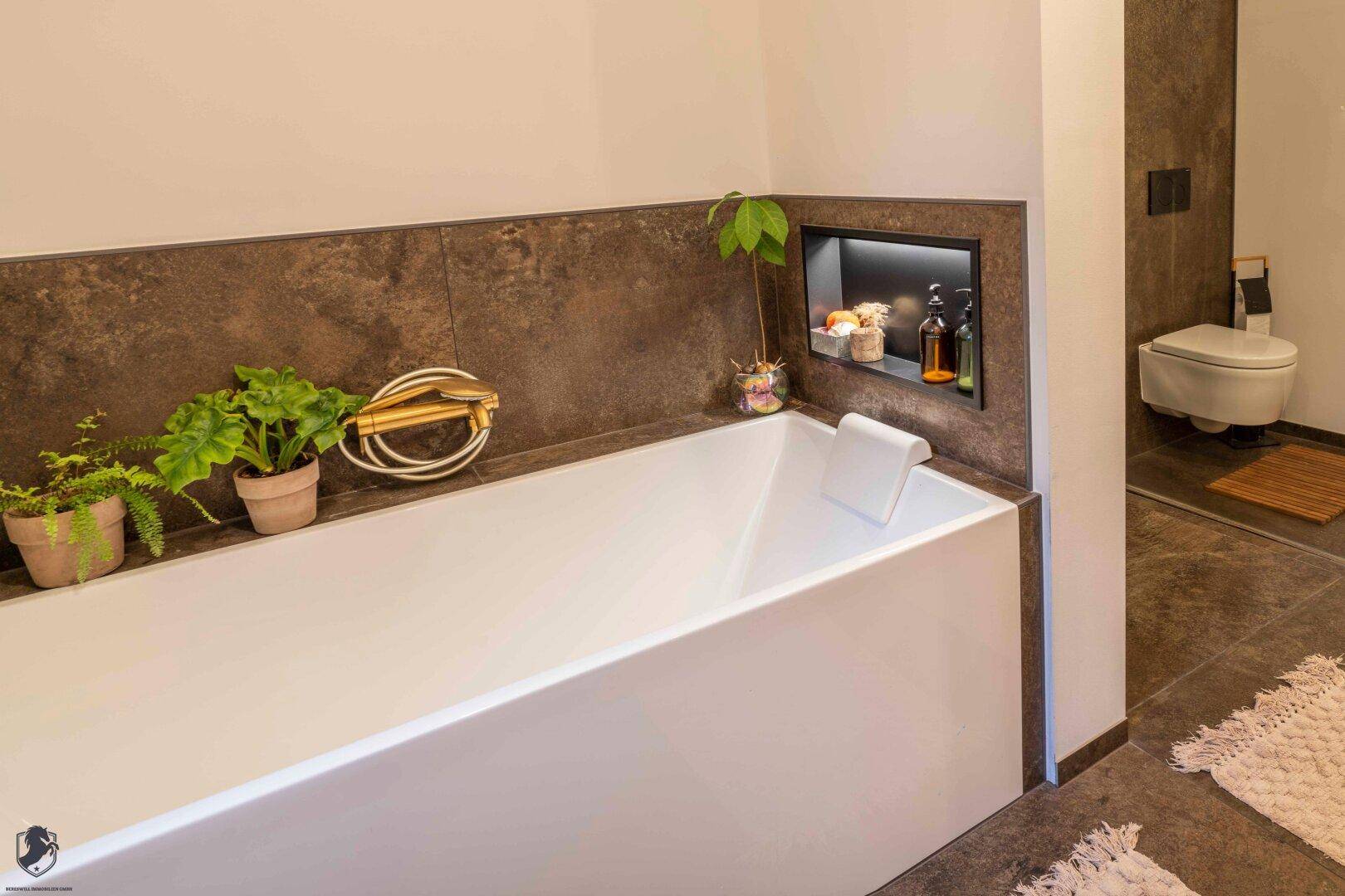 Modernes Badezimmer mit eleganter Badewanne, dunklen Fliesen und Wand-WC.