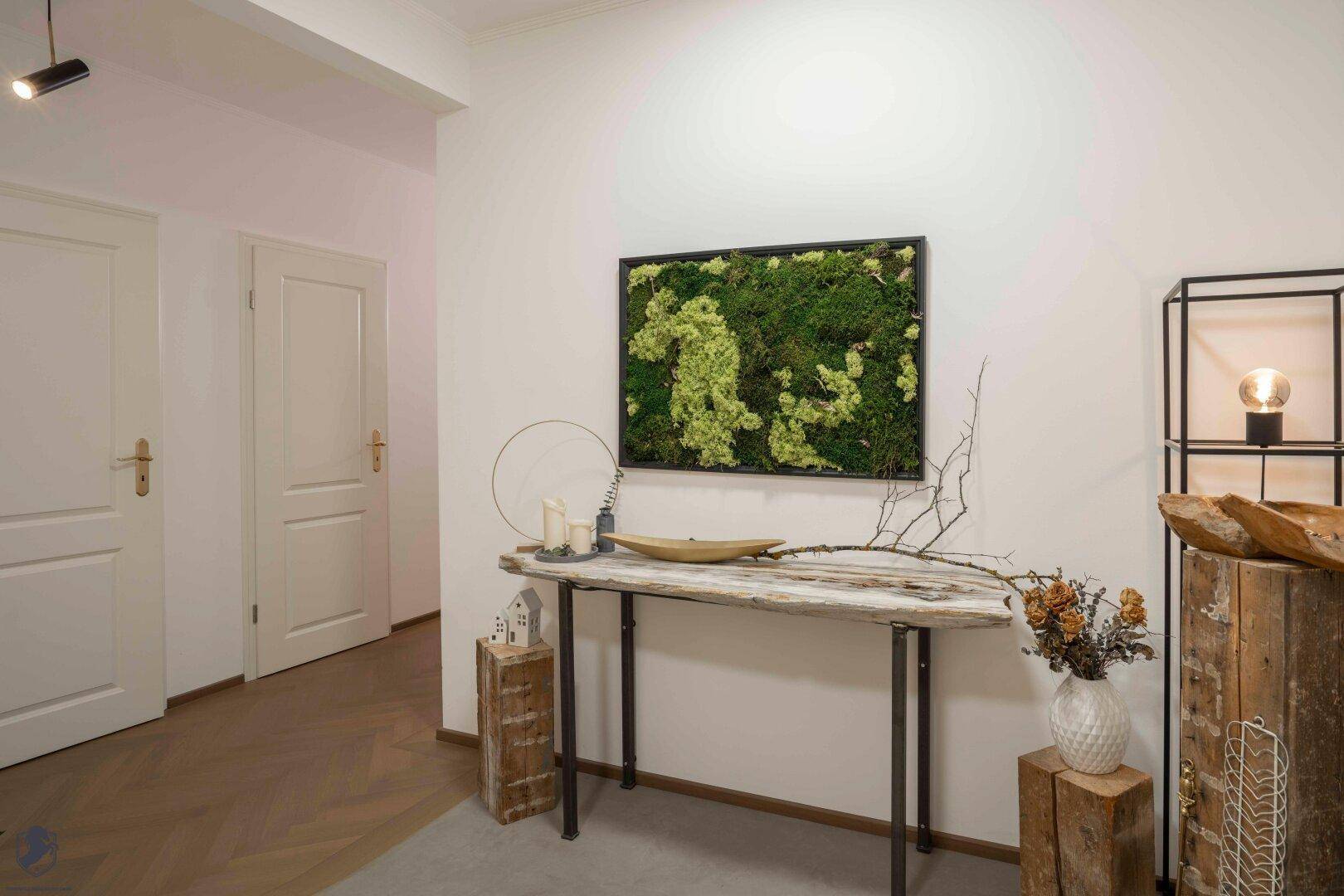 Heller Flurbereich mit moderner Dekoration, Konsolentisch und Moosbild an der Wand.