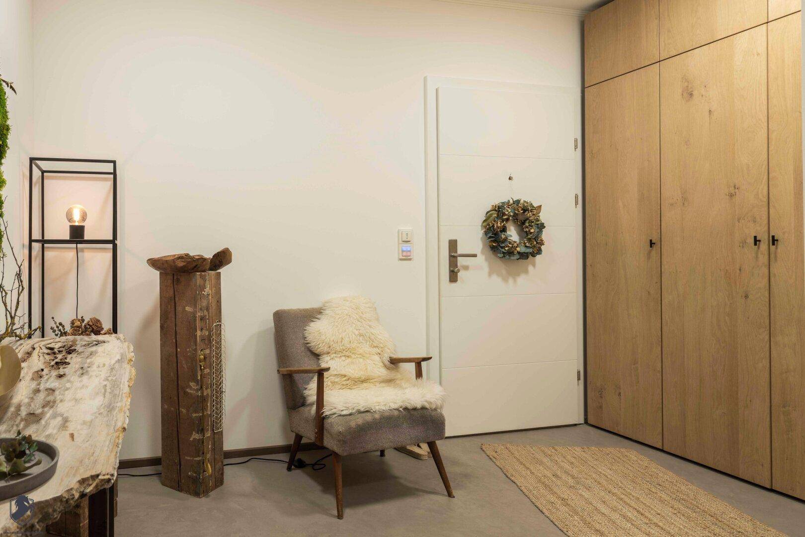 Eingangsbereich mit Holzeinbauschränken, gemütlichem Sessel und moderner Dekoration.