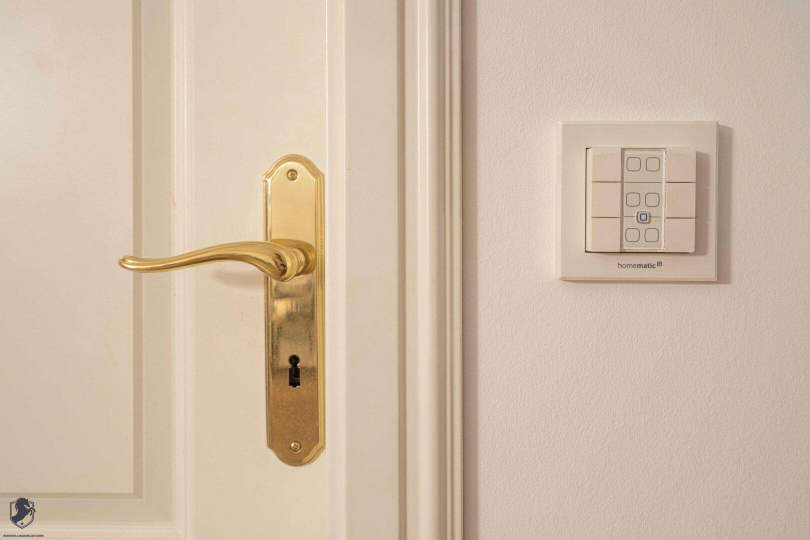 Detailaufnahme einer Tür mit goldener Klinke und einem modernen Smart-Home-Bedienfeld.