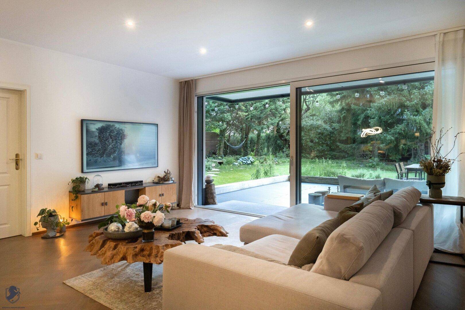 Helles Wohnzimmer mit bequemer Couch und großen Schiebetüren zum Garten.