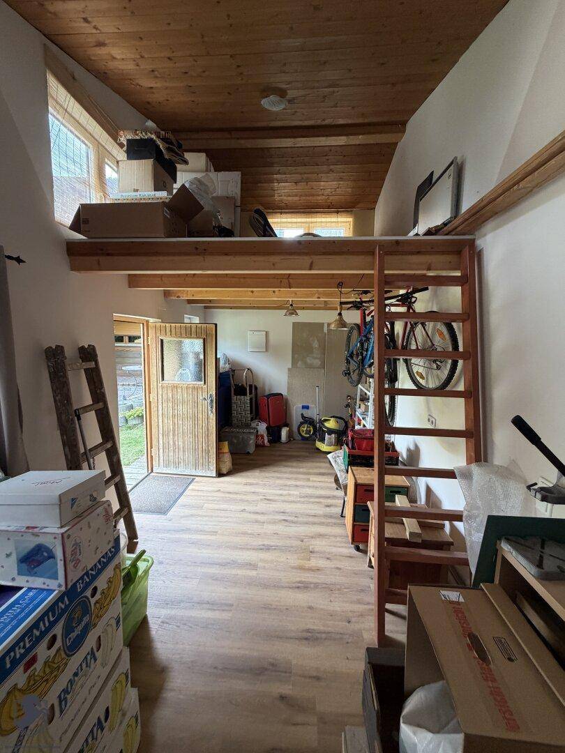 Geräumiger Abstellraum mit Holzdecke, Laminatboden und einer erhöhten Schlaf- oder Lagerfläche.
