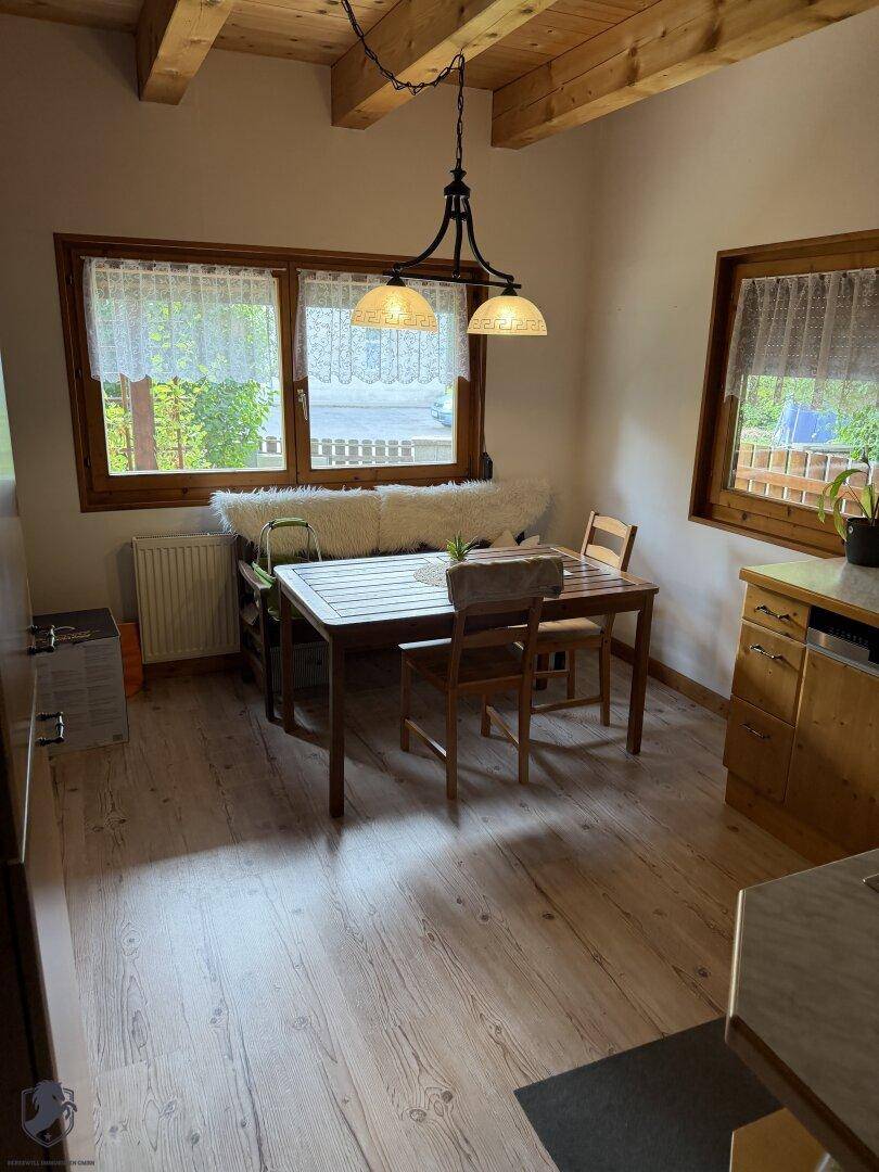 Heller Essbereich mit Holztisch, Sitzbank und Fenstern, die viel Tageslicht hereinlassen.