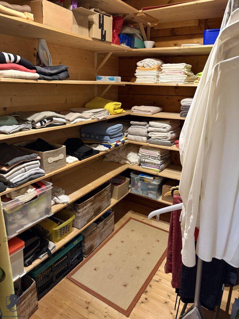 Geräumiger begehbarer Kleiderschrank oder Abstellraum mit vielen Holzregalen für Kleidung und Wäsche.