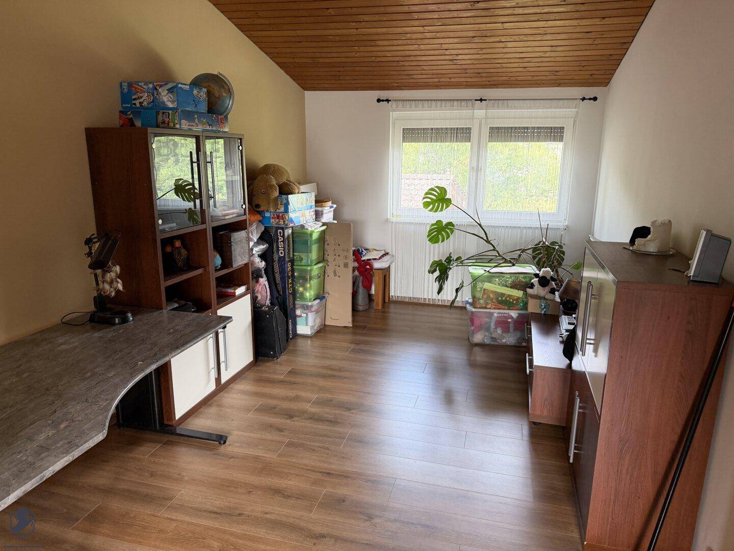 Schlafzimmer oder Arbeitszimmer mit Holzboden, Schreibtisch und Stauraum, hell und geräumig.