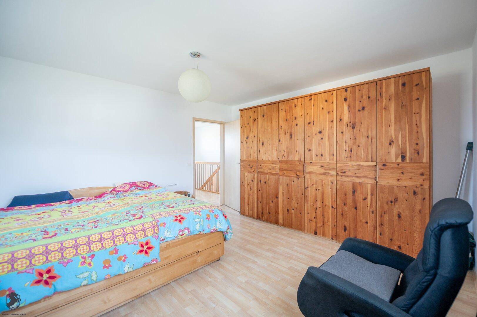 Schlafzimmer mit großem Holzschrank und Doppelbett, bietet viel Stauraum und gemütliche Atmosphäre.