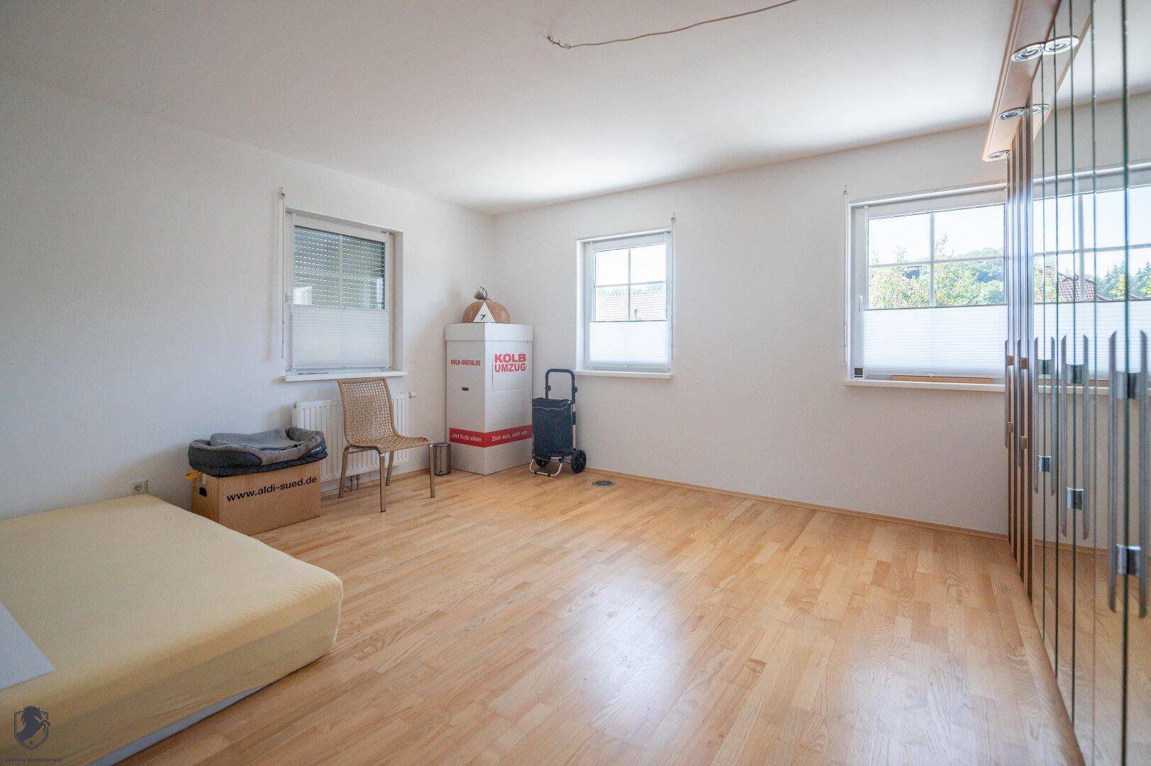 Helles Schlafzimmer mit Laminatboden und großen Fenstern, bereit zur individuellen Gestaltung.