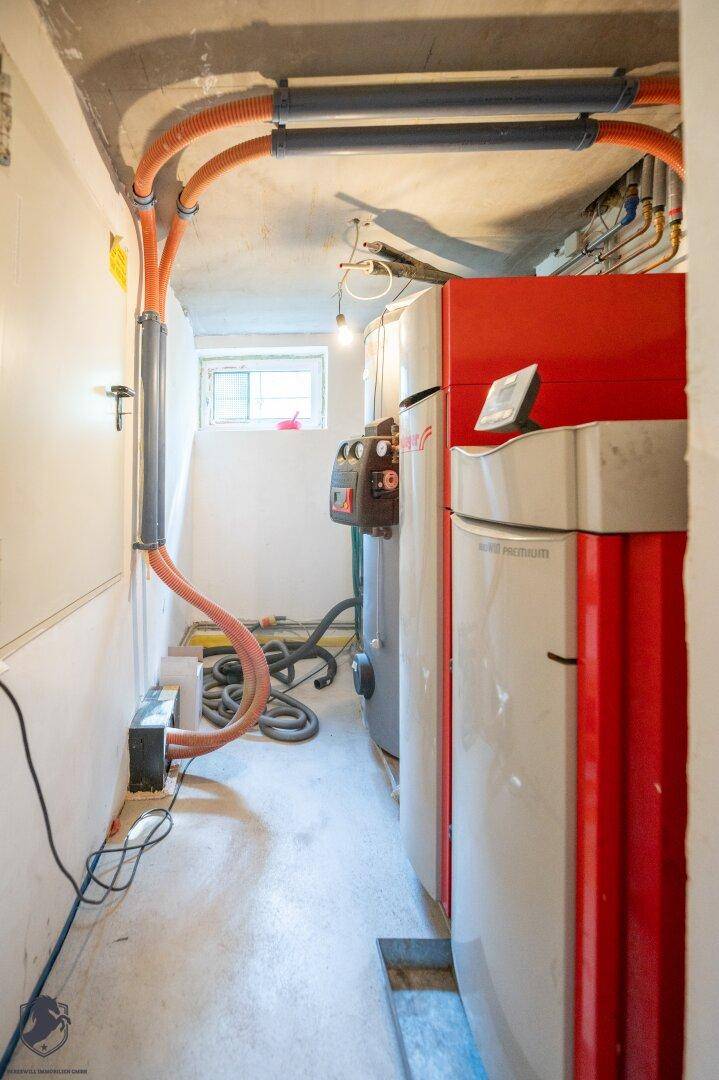 Heizungsraum im Keller mit modernen Anlagen und sichtbaren Installationen für das Gebäude.