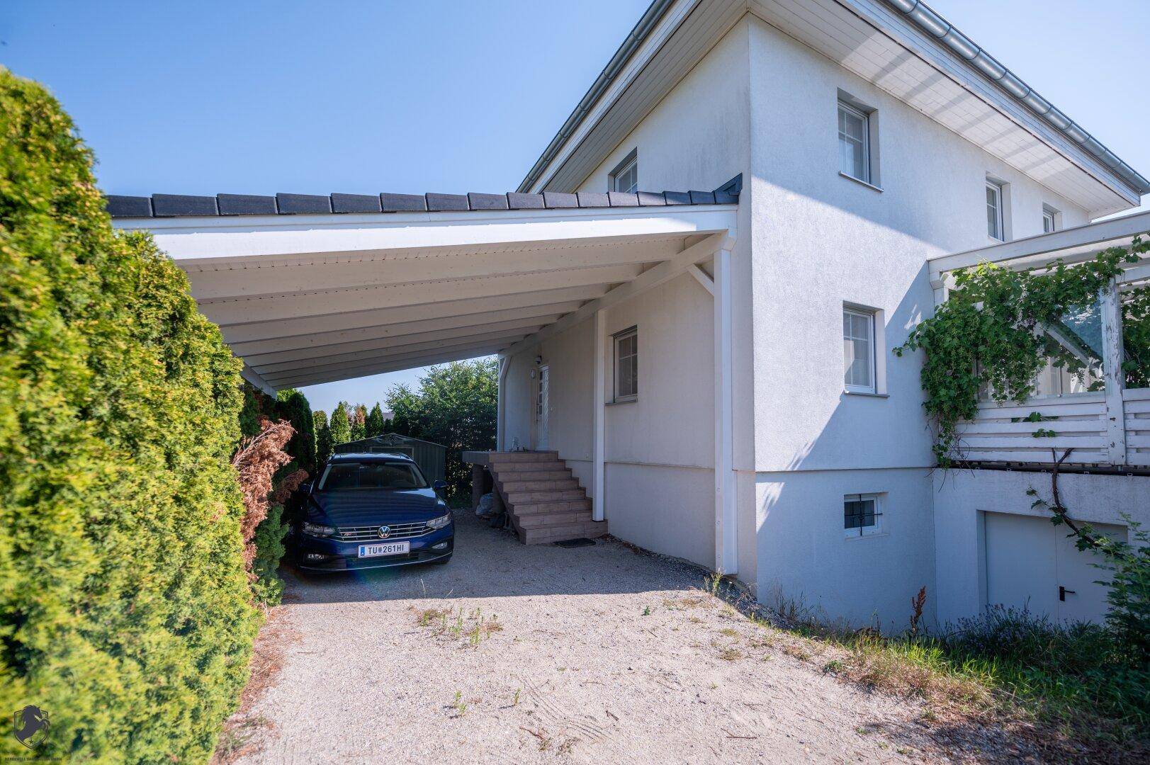 Seitenansicht des Hauses mit überdachtem Carport und Zugang zum Eingangsbereich.