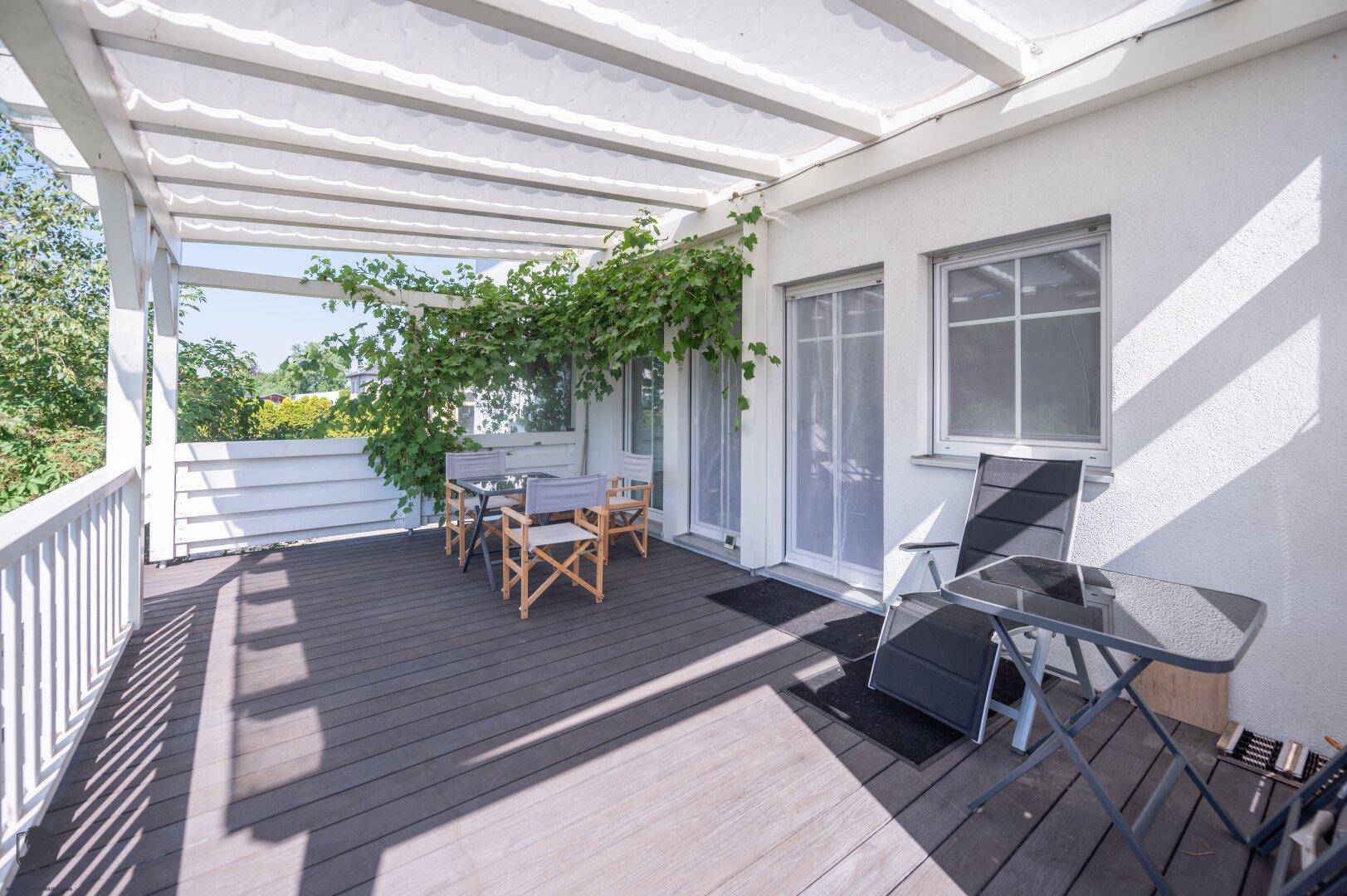 Sonnige Terrasse mit bequemen Liegestühlen, Pergola und Blick ins Grüne.