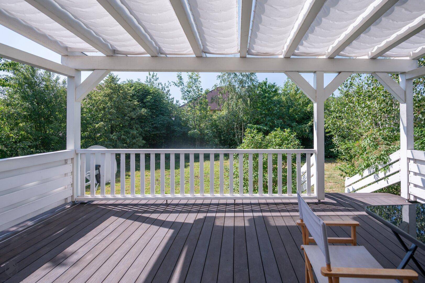 Weitläufiger Blick von der Terrasse in den grünen Garten mit altem Baumbestand.