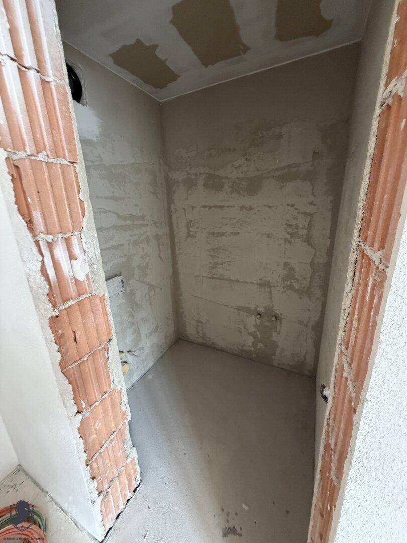 Kleiner Abstellraum im Rohbau mit unverputzten Ziegelwänden und Betonboden, bereit für den Ausbau.