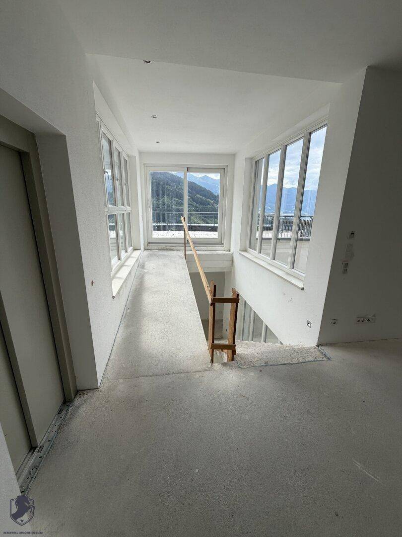 Heller Flurbereich mit großen Fensterfronten, die einen Panoramablick auf die umliegende Berglandschaft bieten.