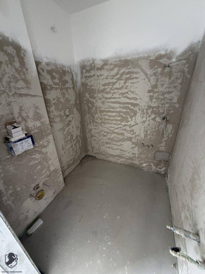 Unfertiges Badezimmer mit vorbereiteten Anschlüssen und rauen Wänden, bereit für den Ausbau.