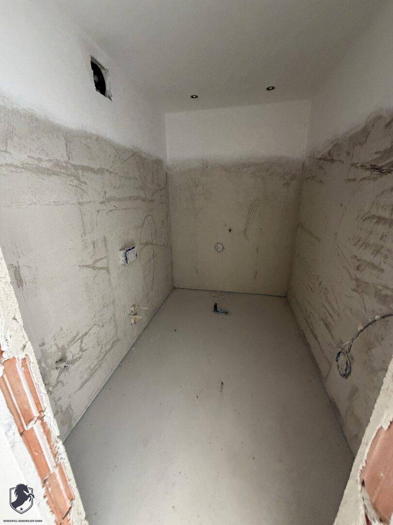Unfertiges Badezimmer mit vorbereiteten Anschlüssen und rauen Wänden, bereit für den Ausbau.