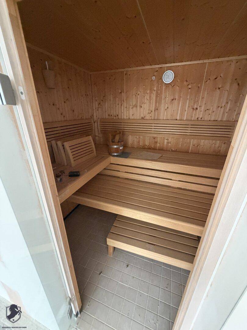 Fertige Sauna mit hellem Holz und mehrstufigen Sitzbänken, einladend zur Entspannung.