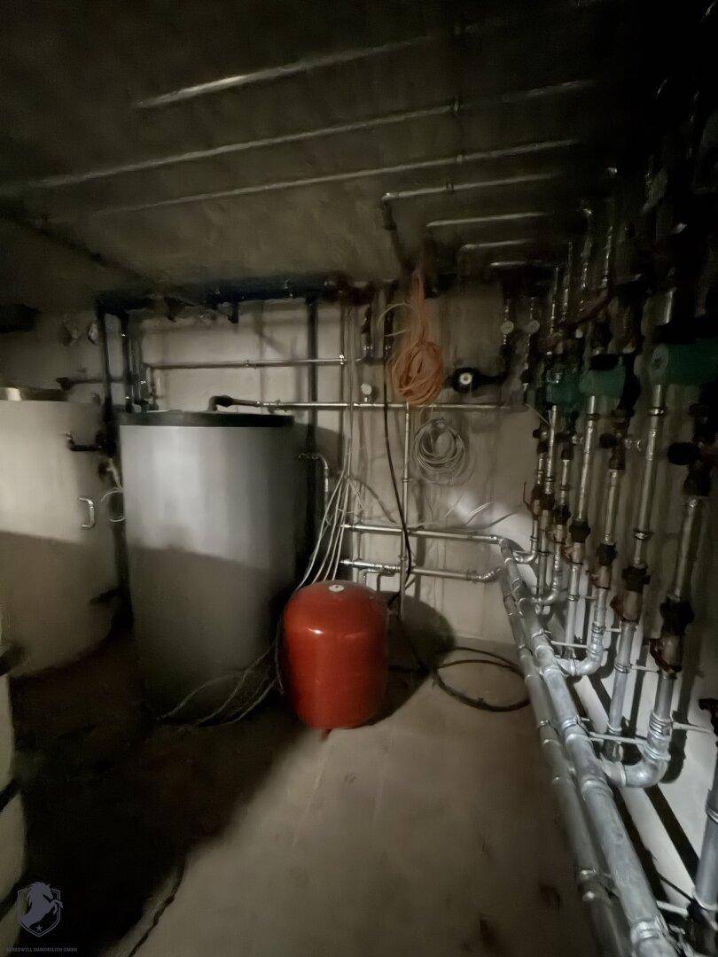 Technikraum im Keller mit zahlreichen Rohren und Warmwasserspeichern für die Gebäudetechnik.