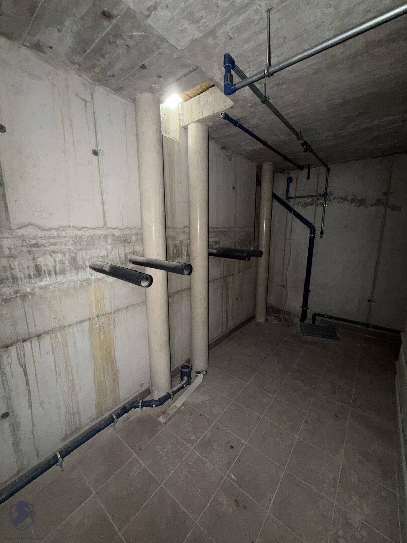 Kellerraum mit sichtbaren Rohren und Betonwänden, bereit für den weiteren Ausbau.