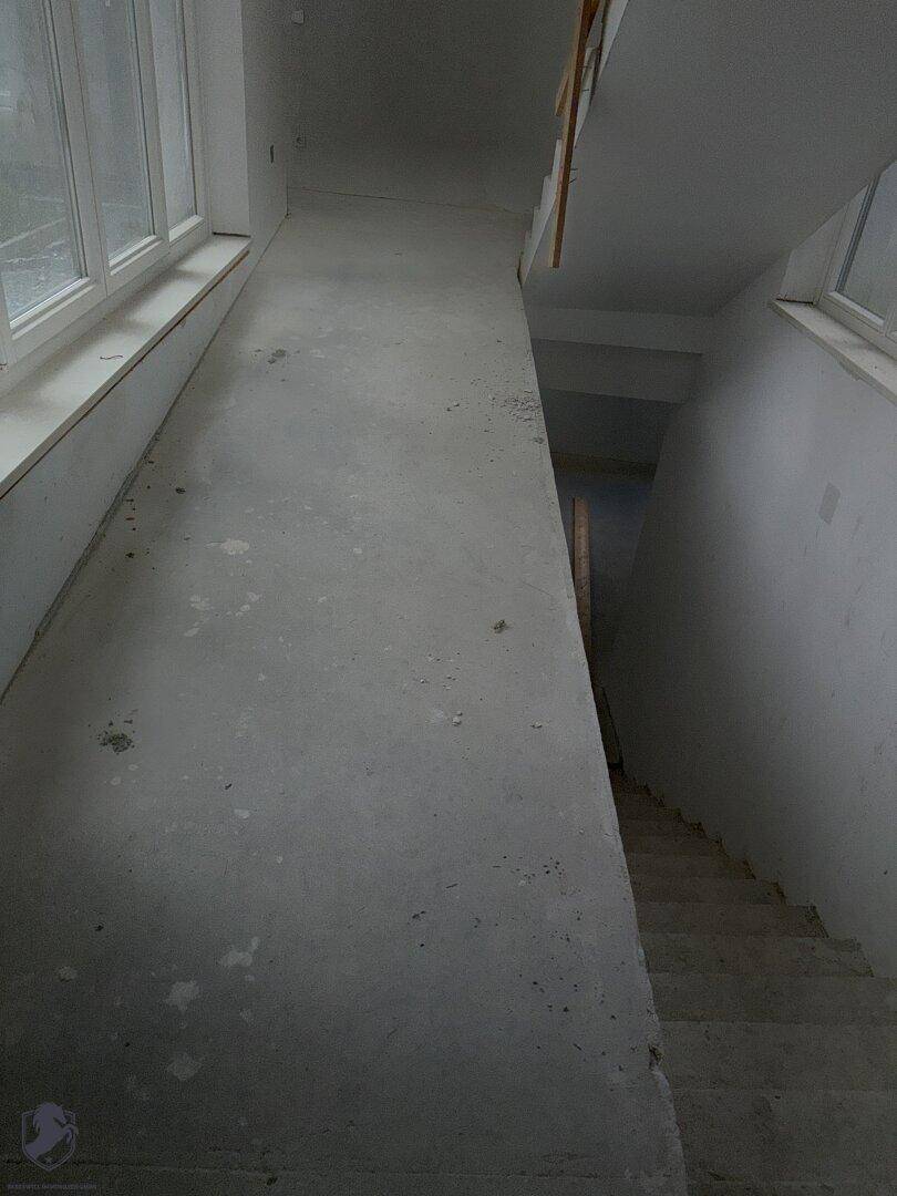 Unfertige Rampe, die zu einer Treppe führt, mit Fenstern für natürliches Licht.
