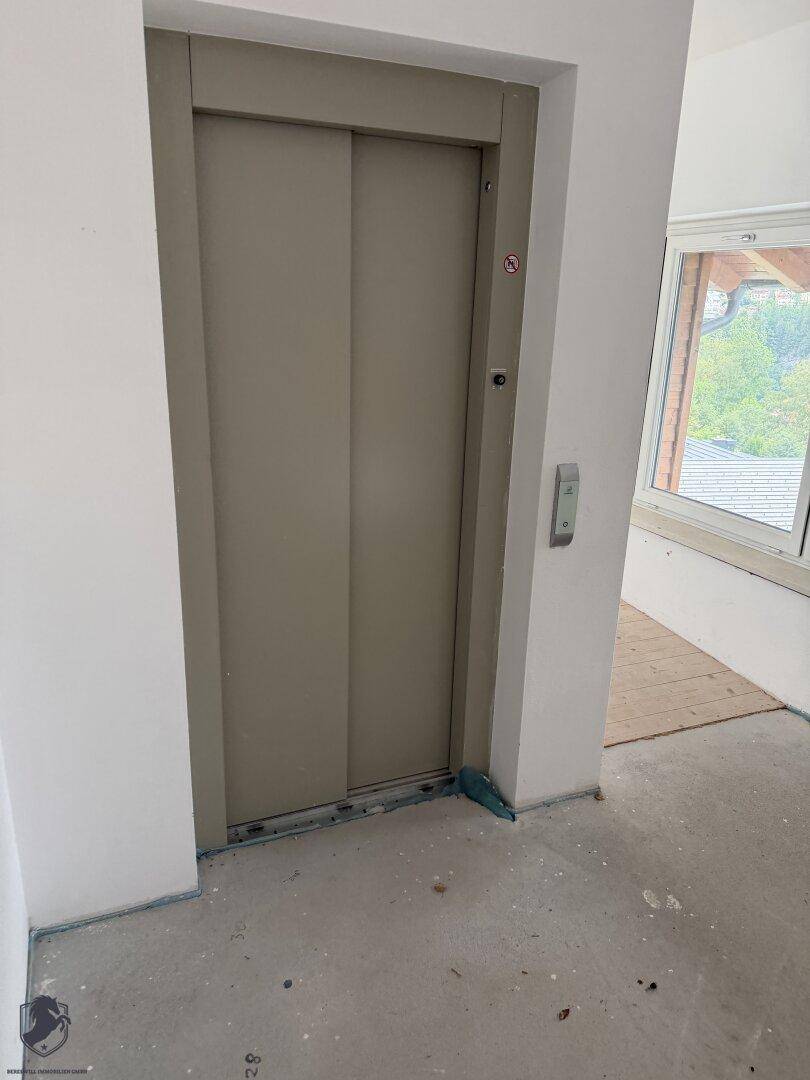 Moderner Aufzug in einem unfertigen Innenbereich mit Fenster und Tageslicht, bereit zur Fertigstellung.