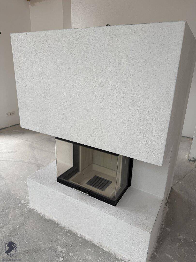 Moderner Kamin mit Glasfront in einem unfertigen Wohnbereich, bereit zur Installation und Nutzung.