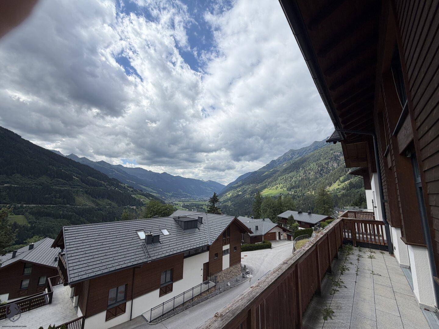 Balkon mit Panoramablick auf ein grünes Tal und die umliegenden Häuser, ideal für Ausblick.