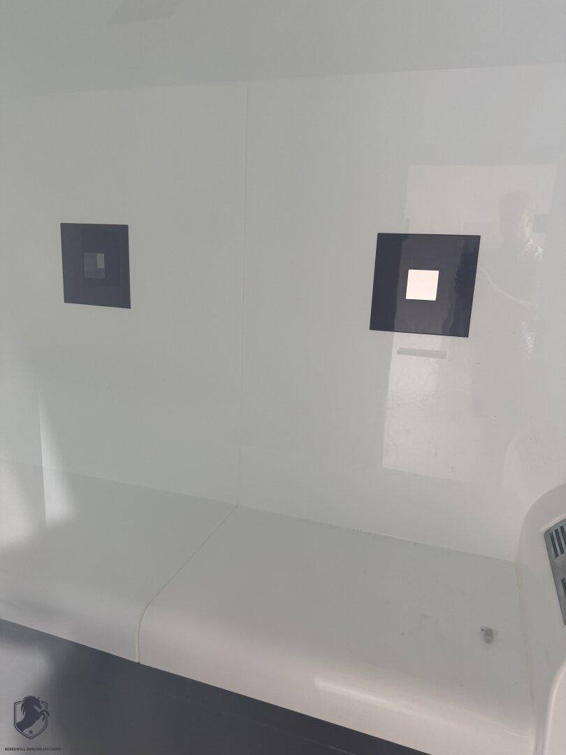 Innenansicht einer modernen Dampfkabine mit weißen Sitzbänken und minimalistischem Design.