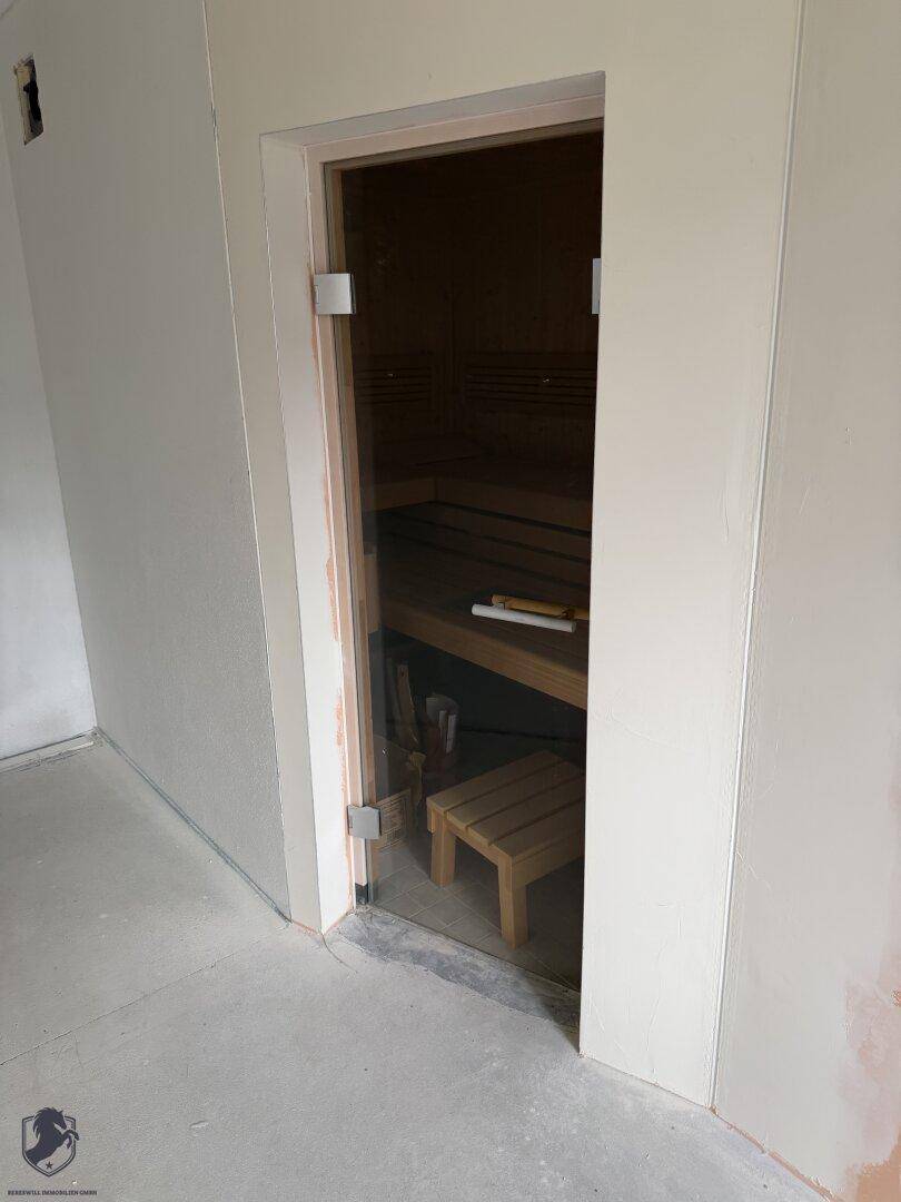 Moderne Sauna mit Holzbänken und Glastür, einladend für entspannende Momente.