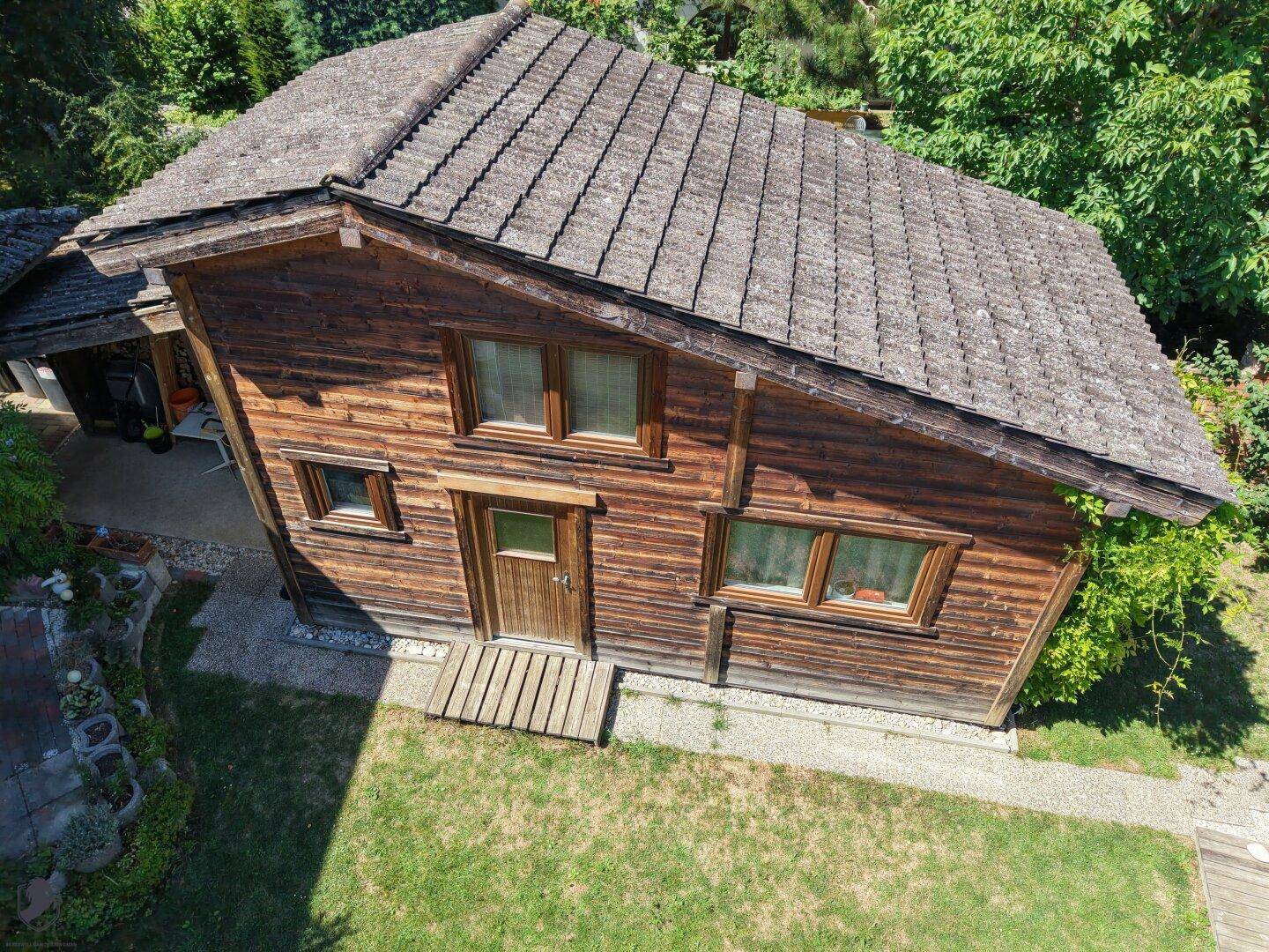 Nahaufnahme der Holzfassade eines Hauses mit markantem Satteldach und kleinen Fenstern.