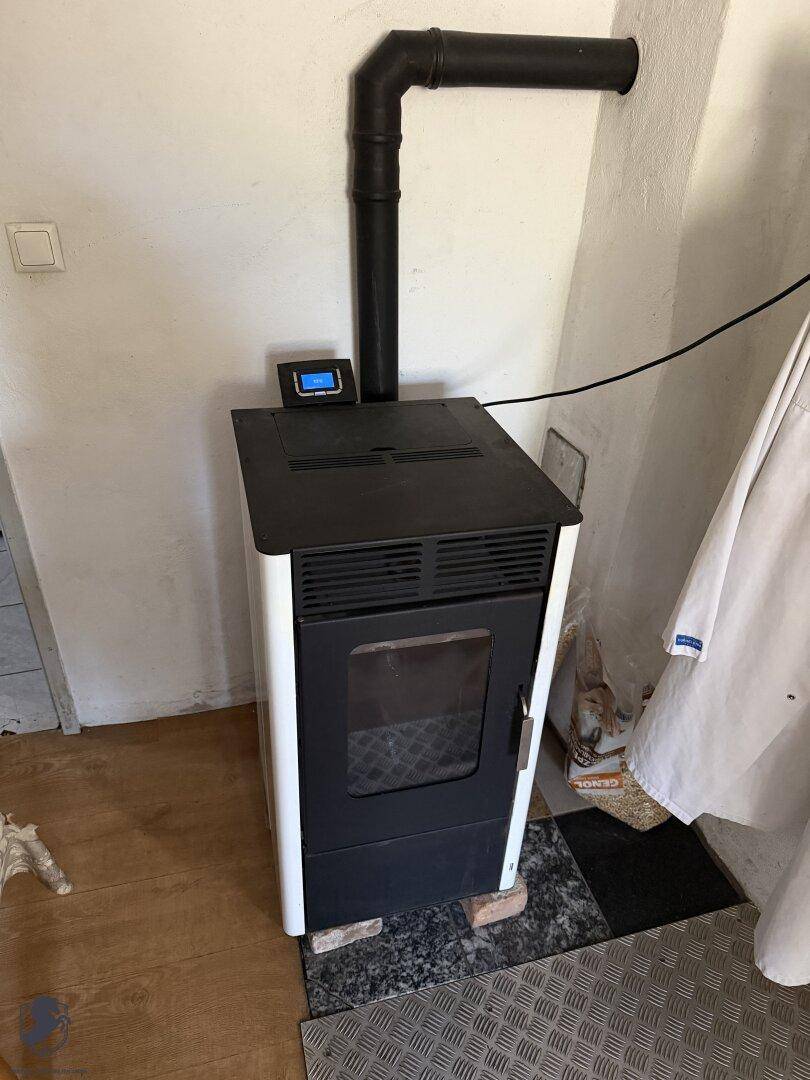 Moderner Pelletofen mit schwarzem Ofenrohr als Heizsystem in einem Innenraum.