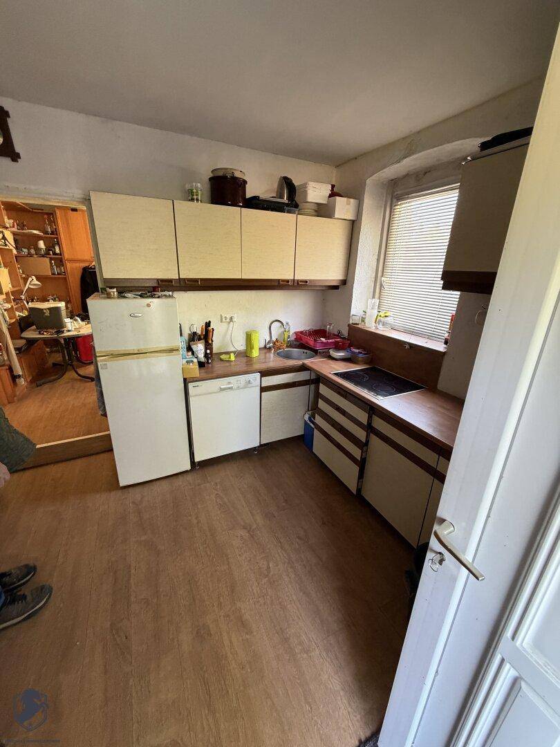 Funktionale Küche mit hellen Schränken, Holz-Arbeitsplatte und integrierten Geräten.