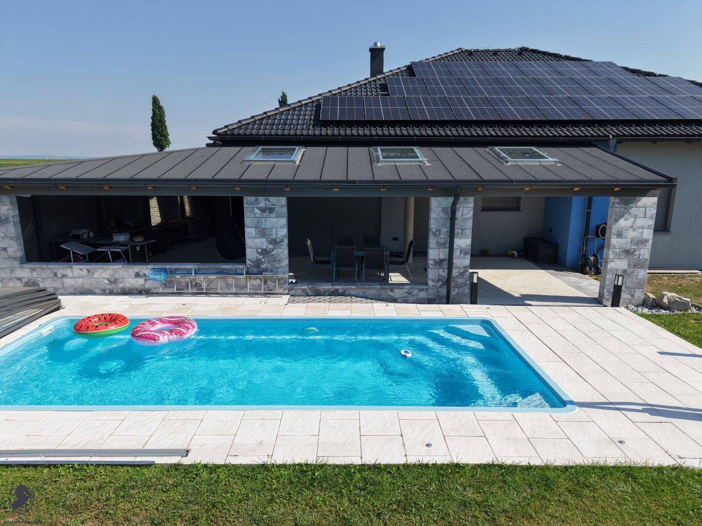 Geräumiger Außenbereich mit Schwimmbecken und einer überdachten Terrasse, ideal für Entspannung und Unterhaltung.