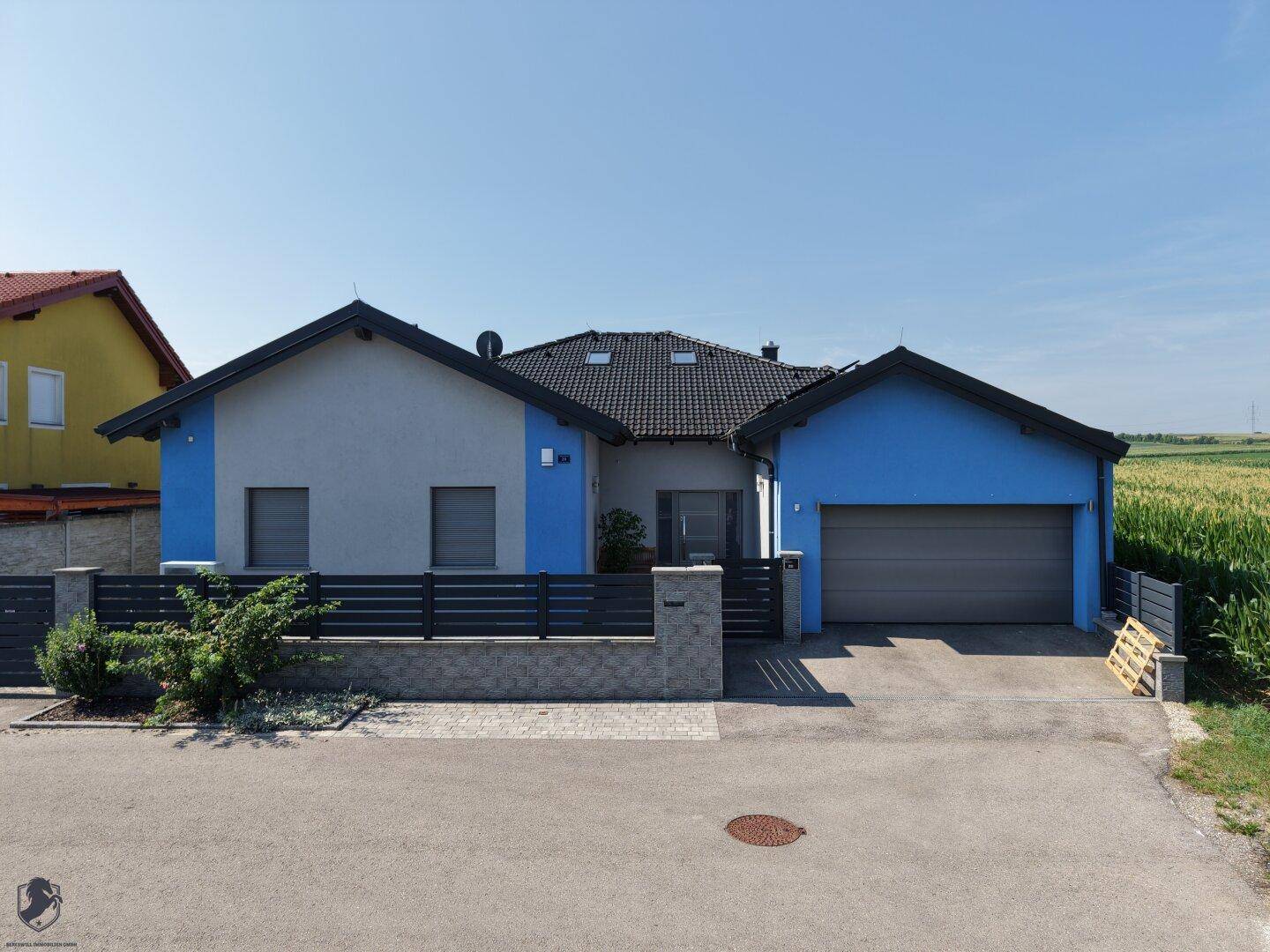 Vorderansicht des modernen Hauses mit Garage, Einfahrt und einem kleinen Vorgarten.