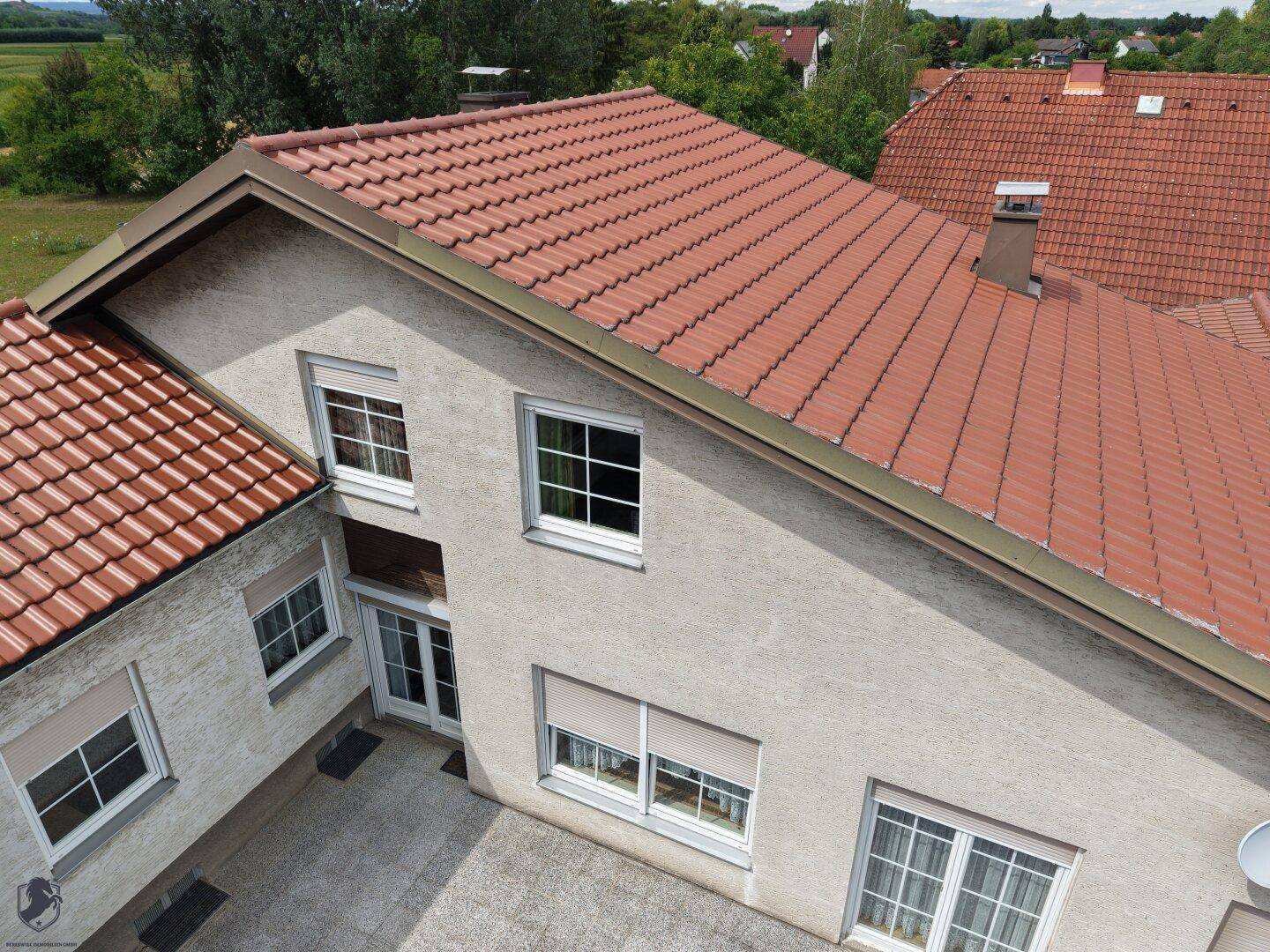 Dachansicht des Hauses mit roten Ziegeln und mehreren Fenstern mit Rollläden.