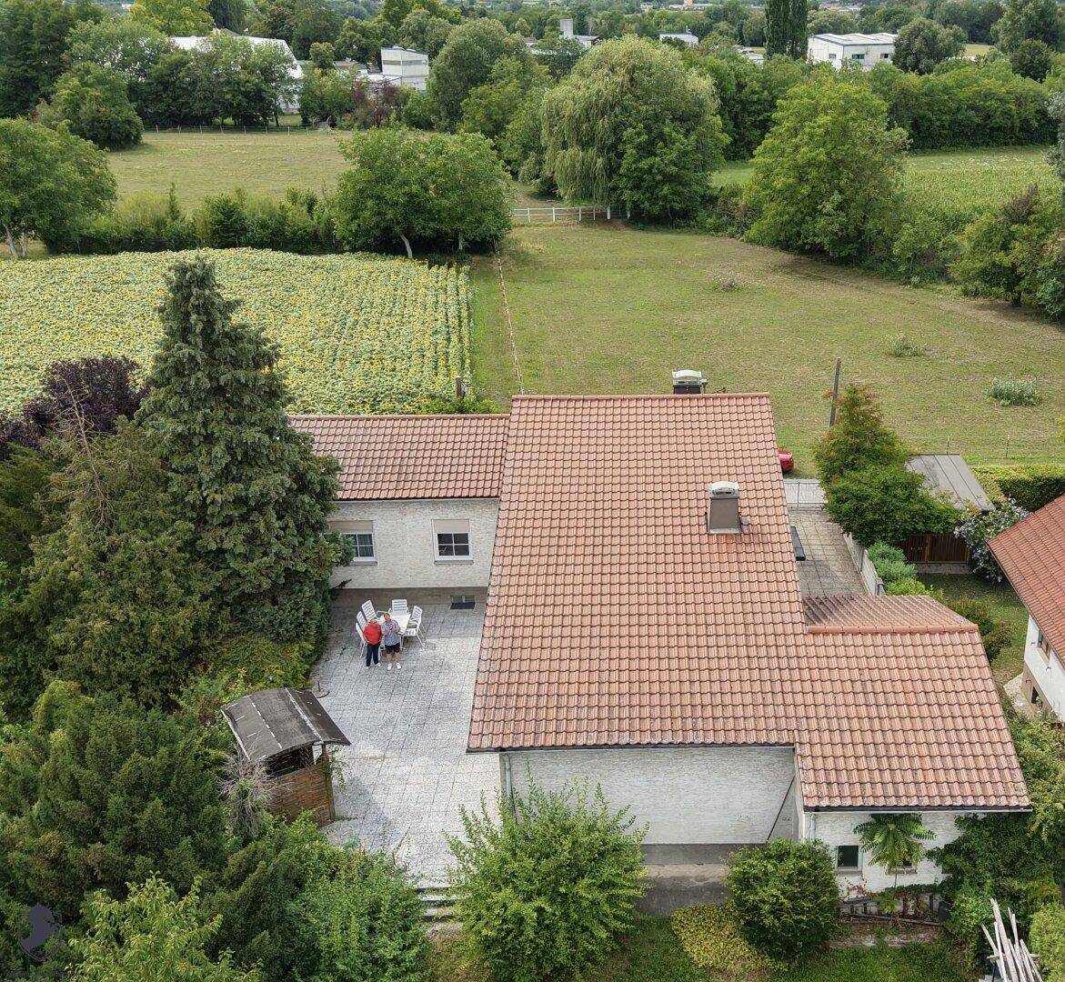 Luftaufnahme des Hauses mit Terrasse und Garten, angrenzend an Felder und grüne Landschaft.