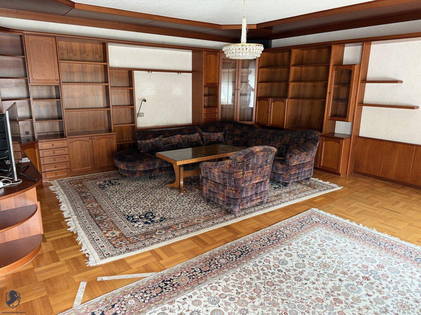 Geräumiges Wohnzimmer mit Holztäfelung, Teppichen und einer großen Sofagarnitur.