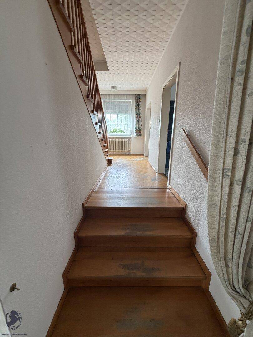 Holztreppe führt zu einem Flur mit Parkettboden und Fenster.