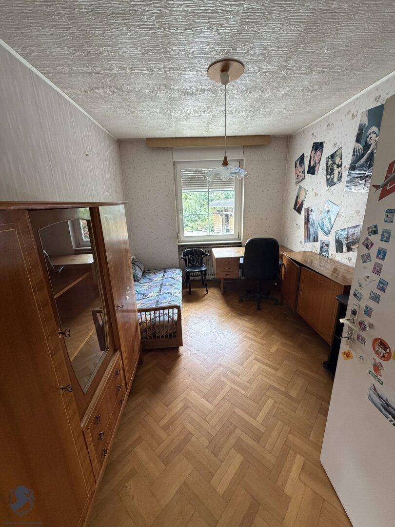 Schlafzimmer oder Kinderzimmer mit Parkettboden, Schrank und Fenster.