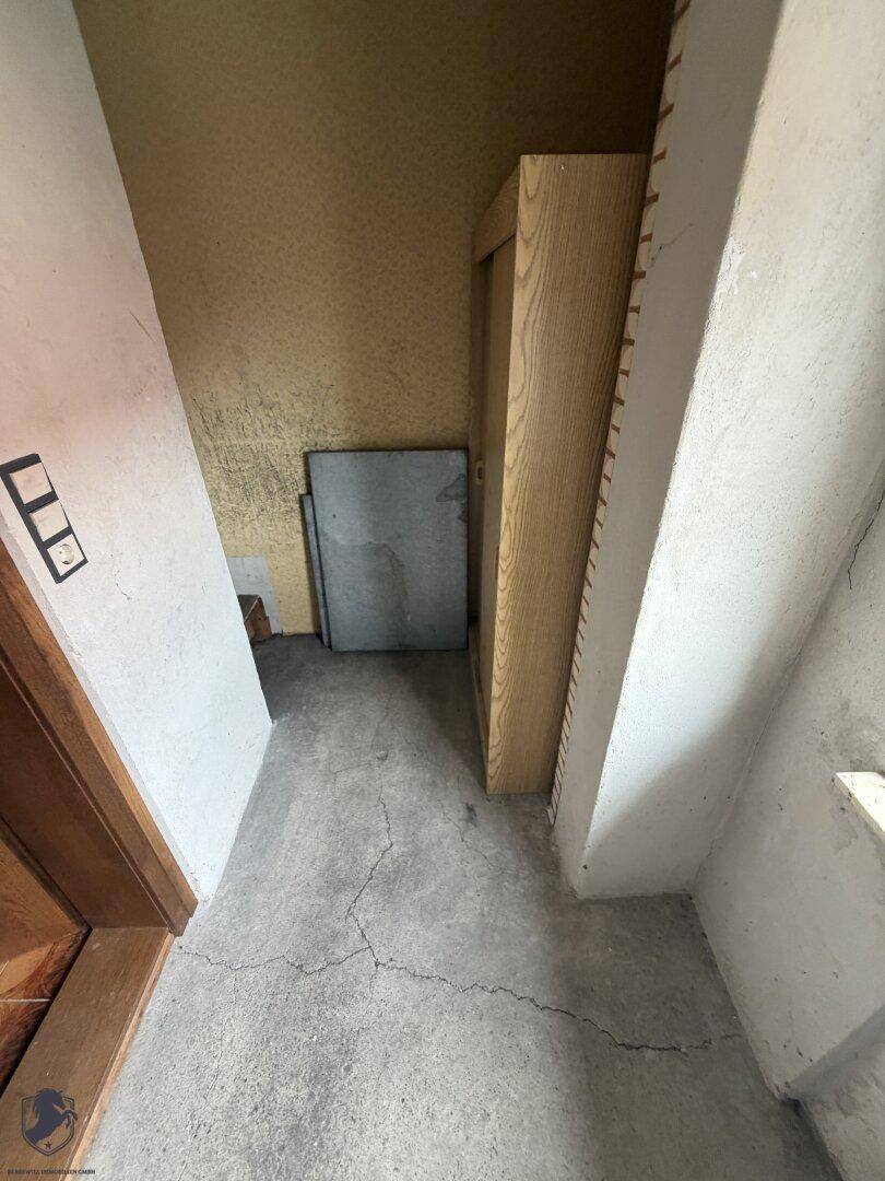 Einfacher Abstellraum mit Betonboden und gelben Wänden, ideal für Lagerzwecke.