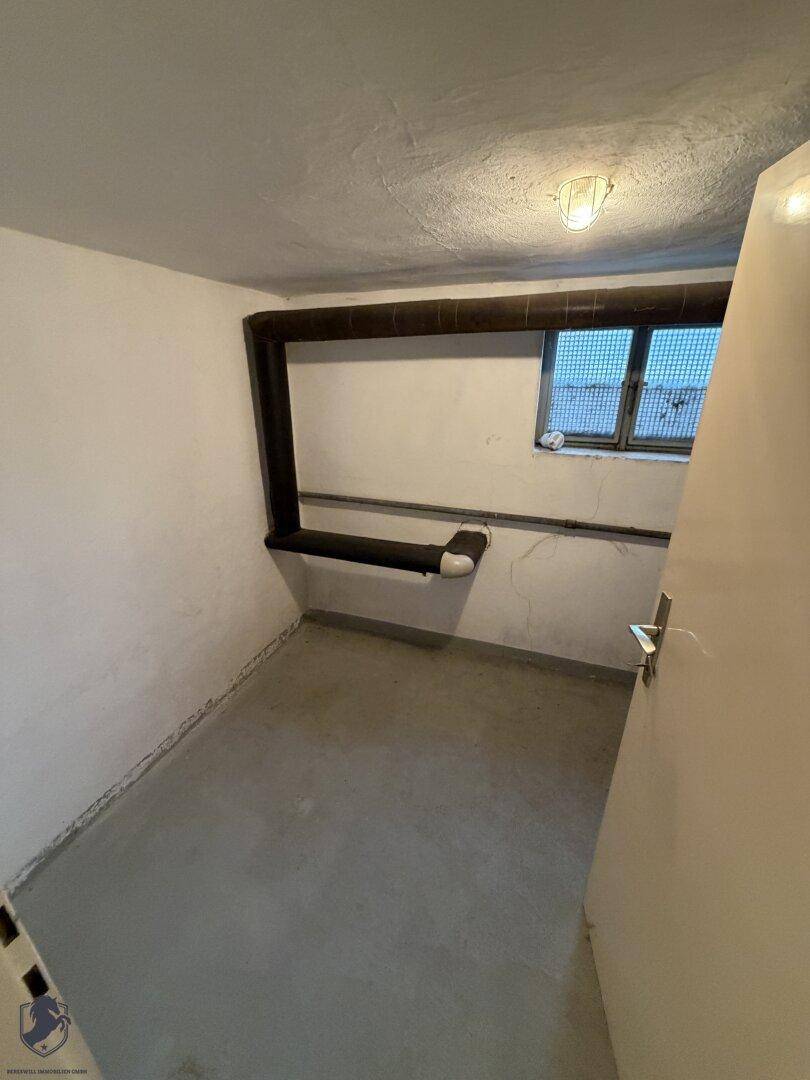 Kellerraum mit Betonboden, weiß gestrichenen Wänden und einem kleinen Fenster.