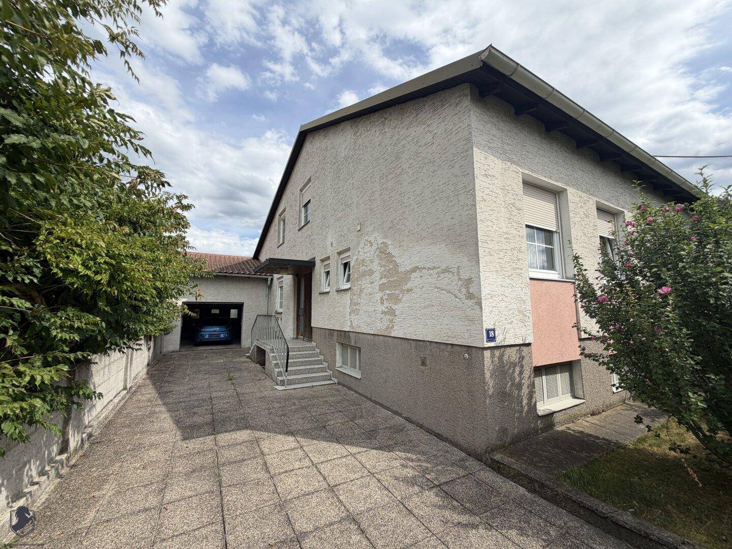Einfamilienhaus mit gepflasterter Auffahrt, Garage und einem kleinen Vorgarten.