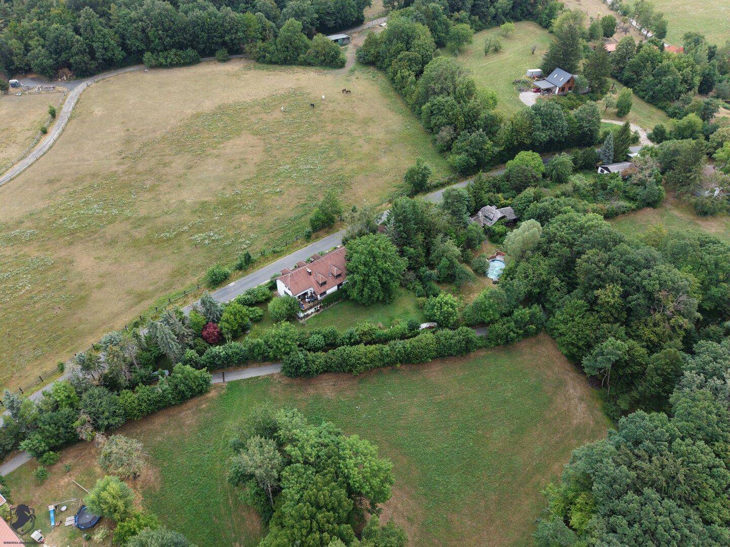 Weitläufige Luftaufnahme des Anwesens, umgeben von Feldern, Wäldern und einer Landstraße.