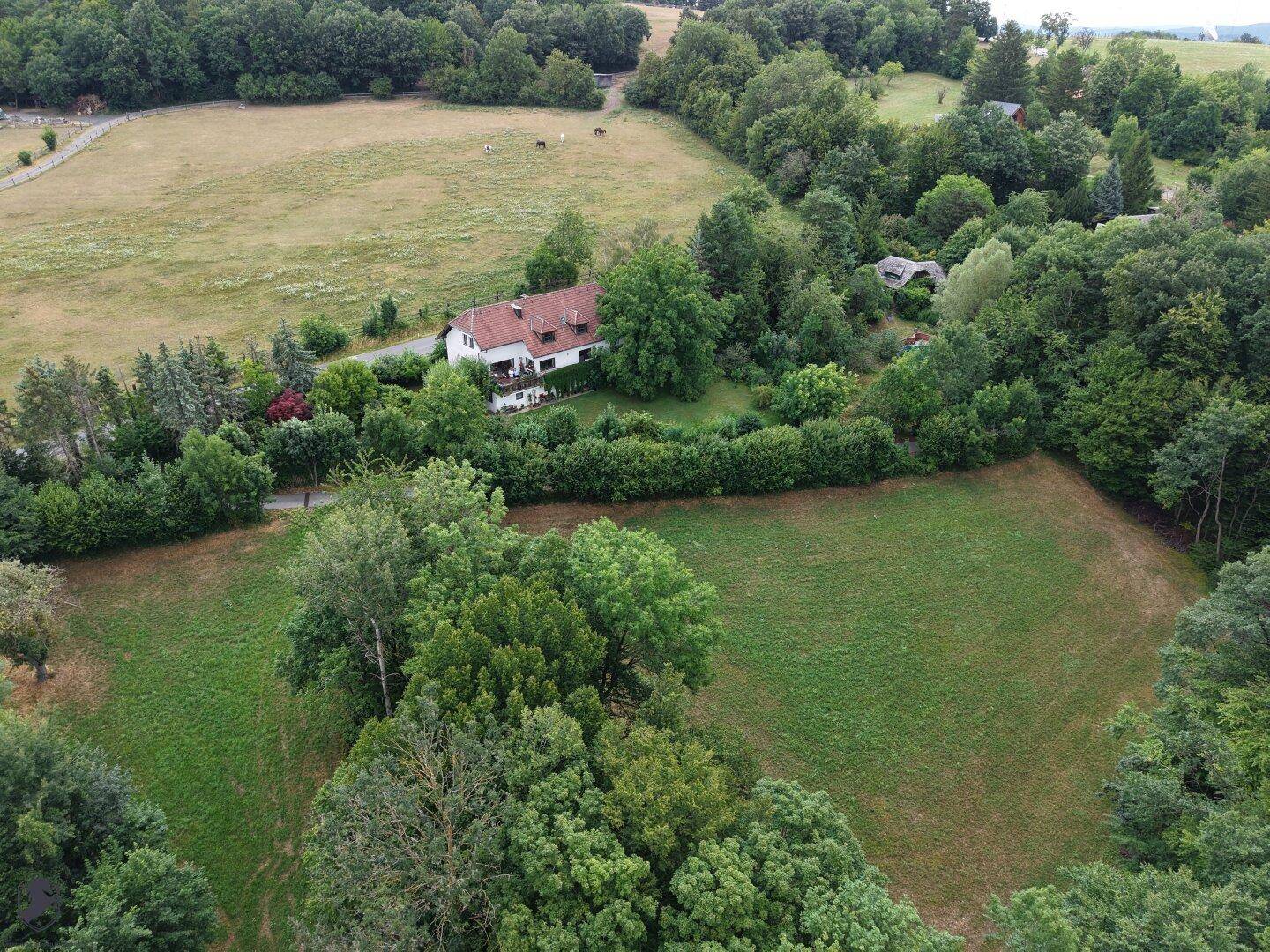 Panoramablick aus der Luft auf das Haus, eingebettet in eine ländliche Landschaft mit weiten Feldern und Wäldern.