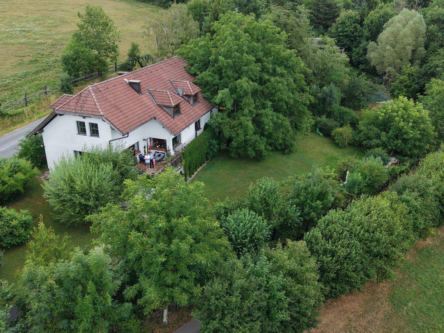 Das Haus aus der Vogelperspektive, mit Balkon und umgeben von einem großen Garten und grünen Wiesen.