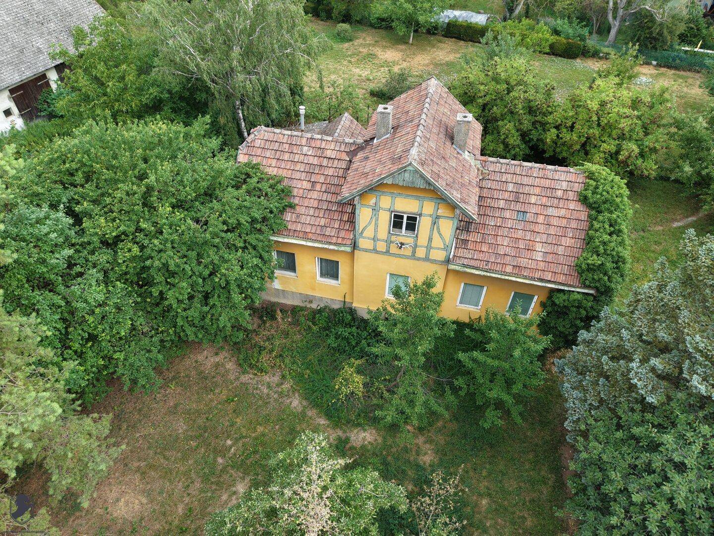 Luftaufnahme eines charmanten Hauses mit großem Garten und altem Baumbestand.