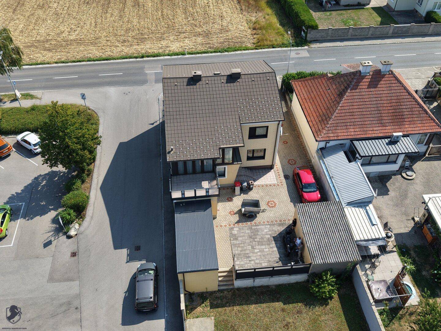 Luftaufnahme des Hauses mit gepflastertem Hof, angrenzender Straße und Feldern.