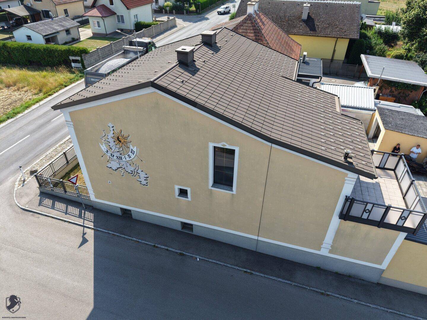Seitenansicht des Hauses mit einer großen Sonnenuhr an der gelben Fassade.