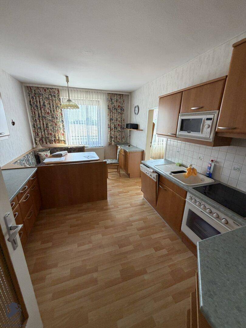 Traditionelle Küche mit Holzeinbauten, Essbereich und Blick nach draußen.