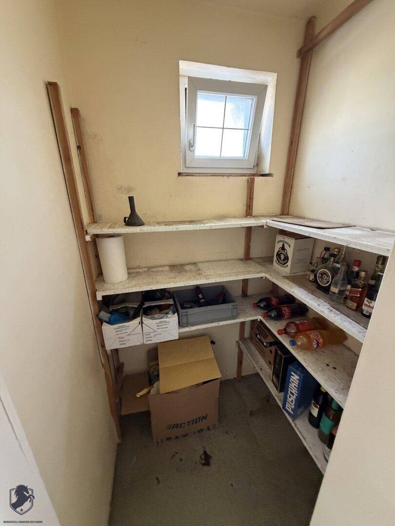 Vorratsraum mit Regalen und einem kleinen Fenster für natürliche Belüftung.